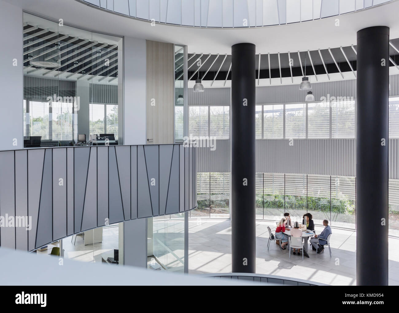 Geschäftsleute treffen sich am Tisch im architektonischen, modernen Büroatrium Stockfoto