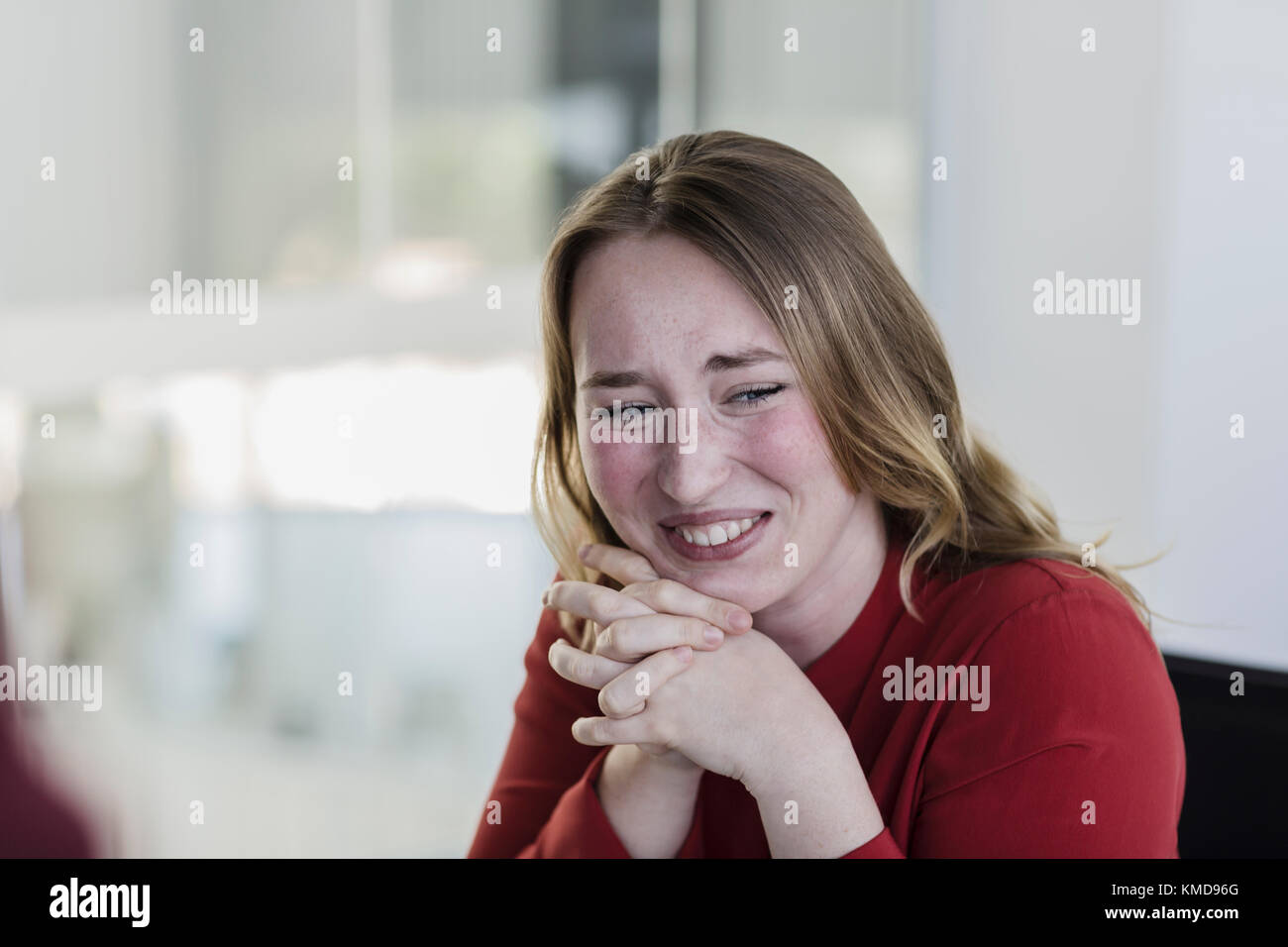 Geschäftsfrau lachend mit Händen zusammengeklemmt Stockfoto