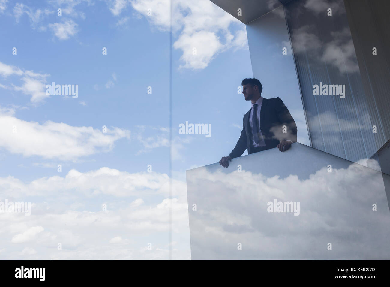 Geschäftsmann auf einem modernen Balkon mit Blick auf den blauen Himmel Und Wolken Stockfoto