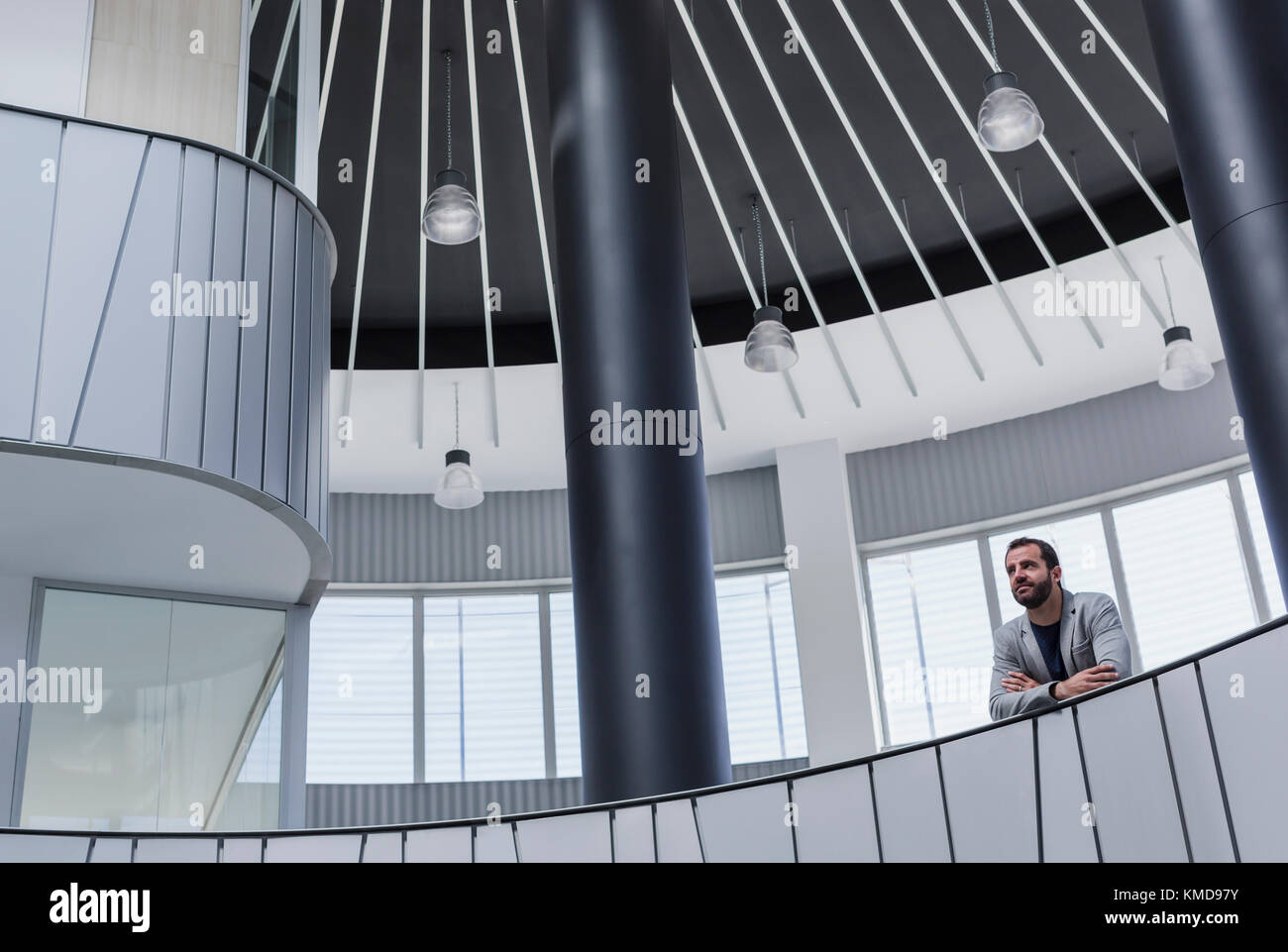 Nachdenklicher Geschäftsmann auf architektonischem, modernem Atrium-Balkon Stockfoto