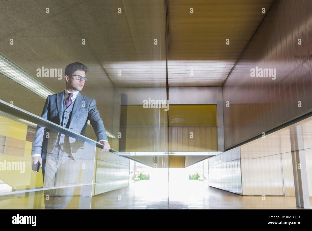 Nachdenklicher Geschäftsmann, der auf ein modernes Bürofenster schaut Stockfoto