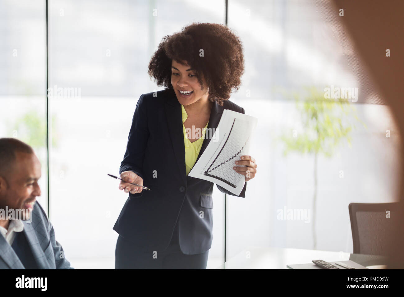 Lächelnde Geschäftsfrau mit Papierkram, die das Meeting leitet Stockfoto