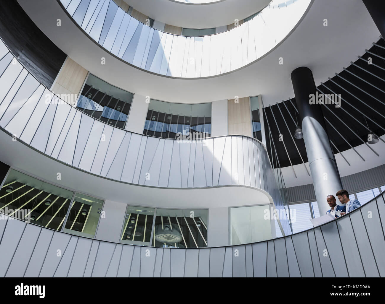 Geschäftsleute diskutieren Papierkram auf architektonischen, modernen Büro Atrium Balkon Stockfoto