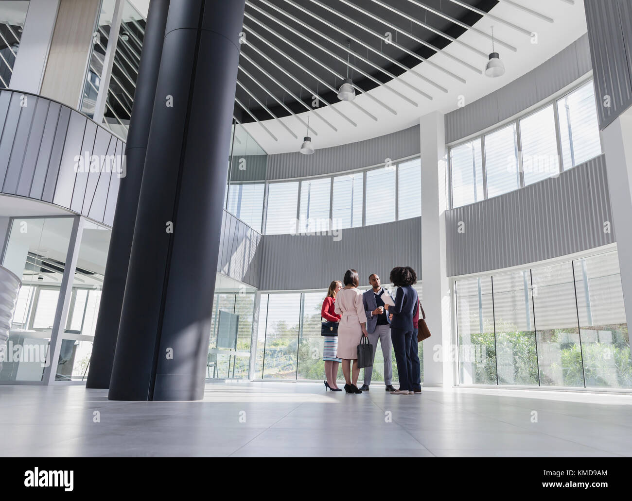 Geschäftsleute unterhalten sich in einer modernen, architektonischen Bürolobby Stockfoto