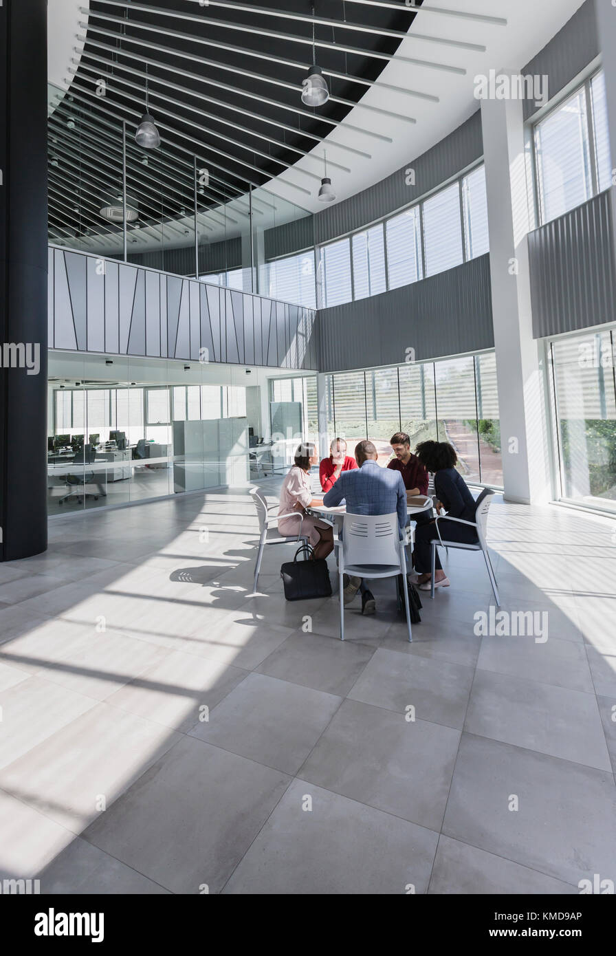 Geschäftsleute treffen sich am Tisch im modernen Büroatrium Stockfoto