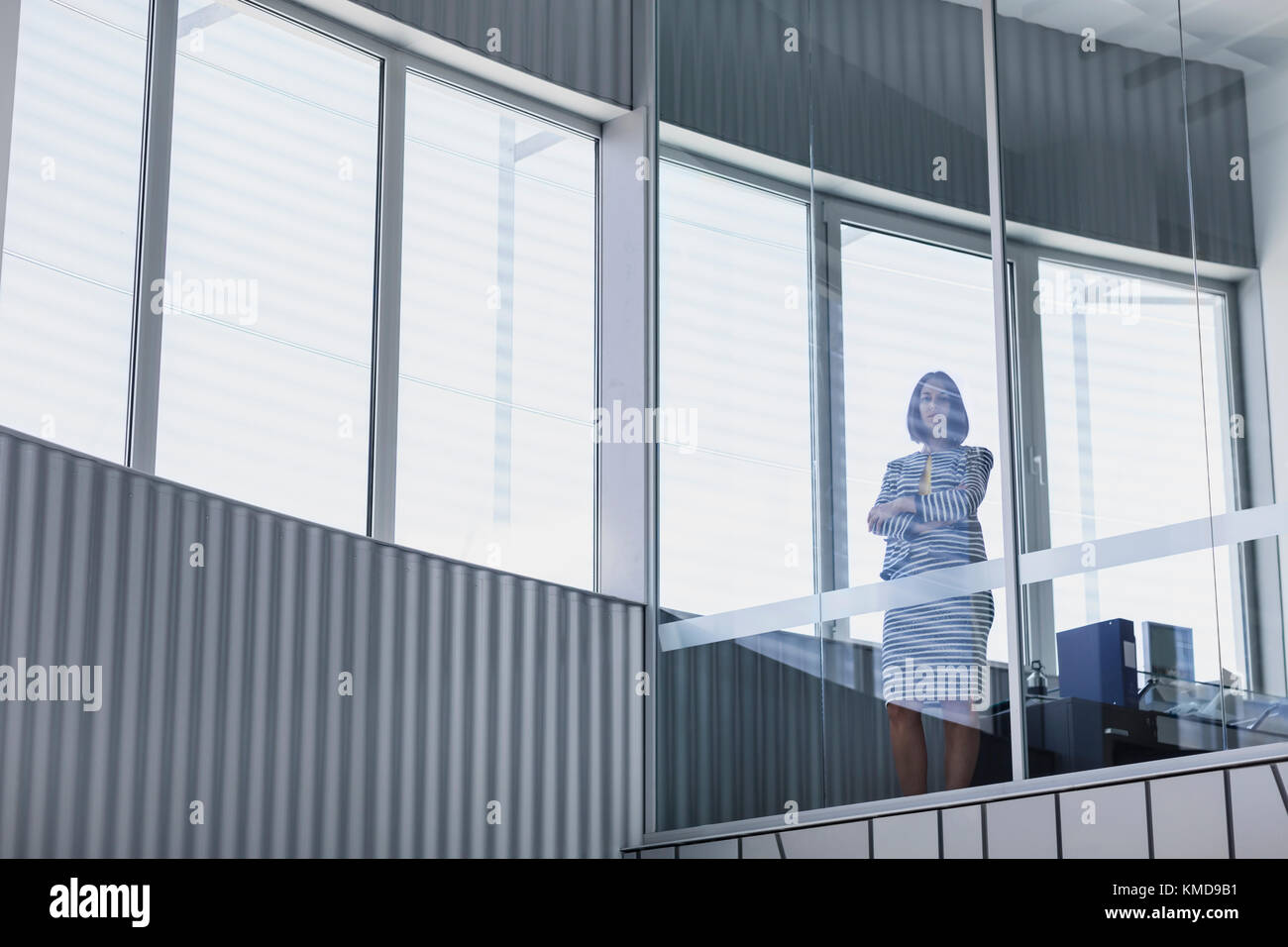 Portrait selbstbewusste Geschäftsführerin Geschäftsfrau steht am modernen Bürofenster Stockfoto