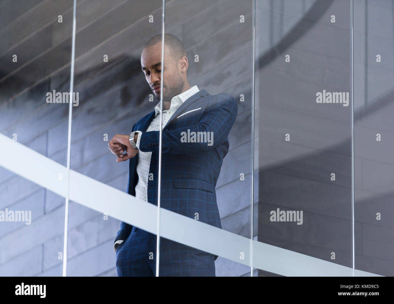 Geschäftsmann überprüft Armbanduhr am modernen Bürofenster Stockfoto