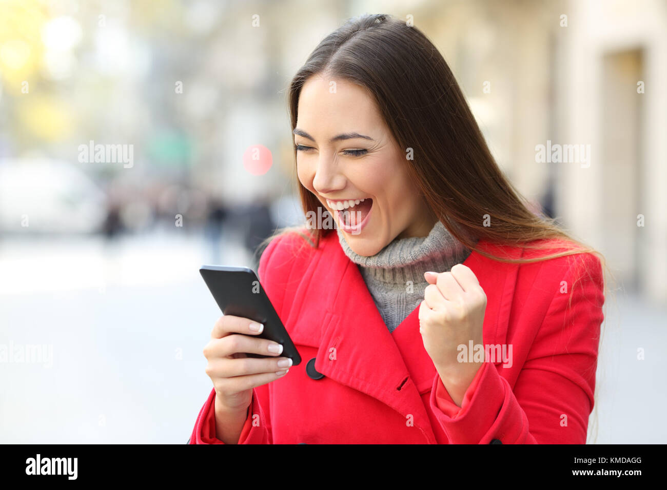 Portrait von eine aufgeregte Frau trägt einen roten Mantel gewinnen auf der Linie draußen auf der Straße im Winter Stockfoto