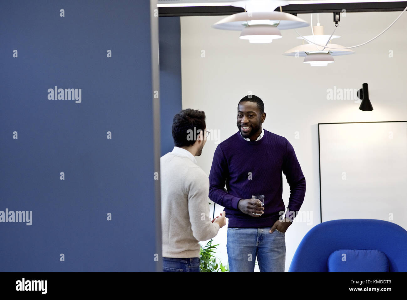 Informelle schwarzer Geschäftsmann in einem modernen Büro Lächeln und Lachen mit einem kaukasischen Kollegen während einer Pause von der Arbeit Stockfoto