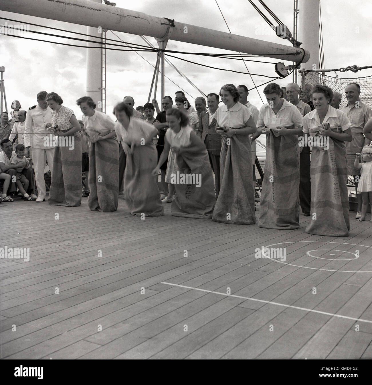 1950, historische, Schiff deck Spiele, weibliche Passagiere in postsäcken bis Zeile für ein Rennen auf dem Deck eines Union-Castle mailship Rubrik für Südafrika beobachtet von den anderen Passagieren und der Crew. Die union-castle Reederei mit Dampfer, waren eine beliebte Art und Weise zu diesem Zeitpunkt für eine Vielzahl von verschiedenen Menschen, Unternehmer, Staatsmänner, Reisende, die Einwanderer plus Fracht und Post ein Fernnetz für Übersee Ziel zu erreichen. Stockfoto