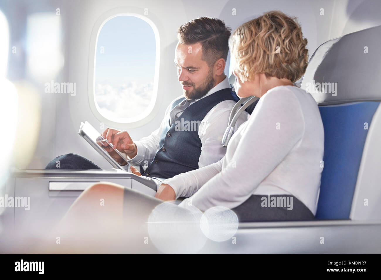 Geschäftsmann und Geschäftsfrau mit digitalen Tablet im Flugzeug Stockfoto
