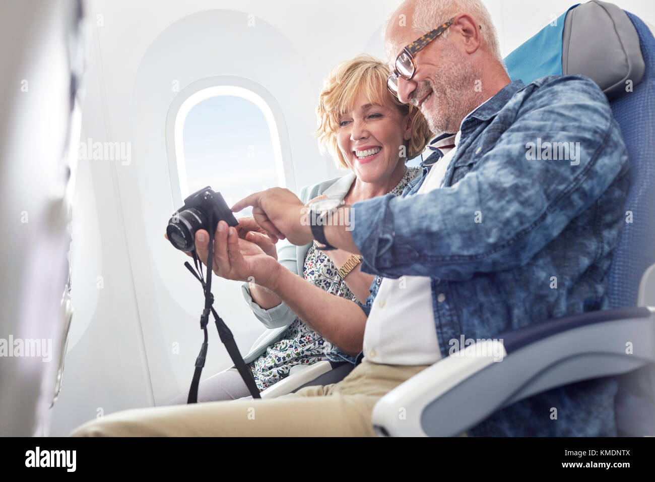 Reifes Paar Blick auf Fotos auf Digitalkamera im Flugzeug Stockfoto