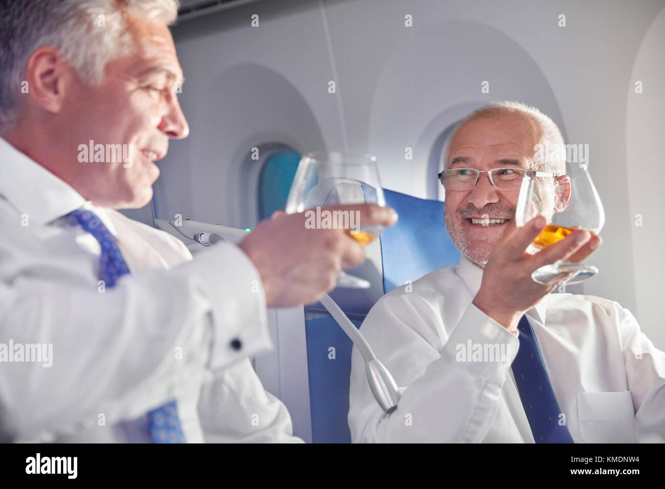 Geschäftsmann toasting Whiskey Gläser in erster Klasse im Flugzeug Stockfoto