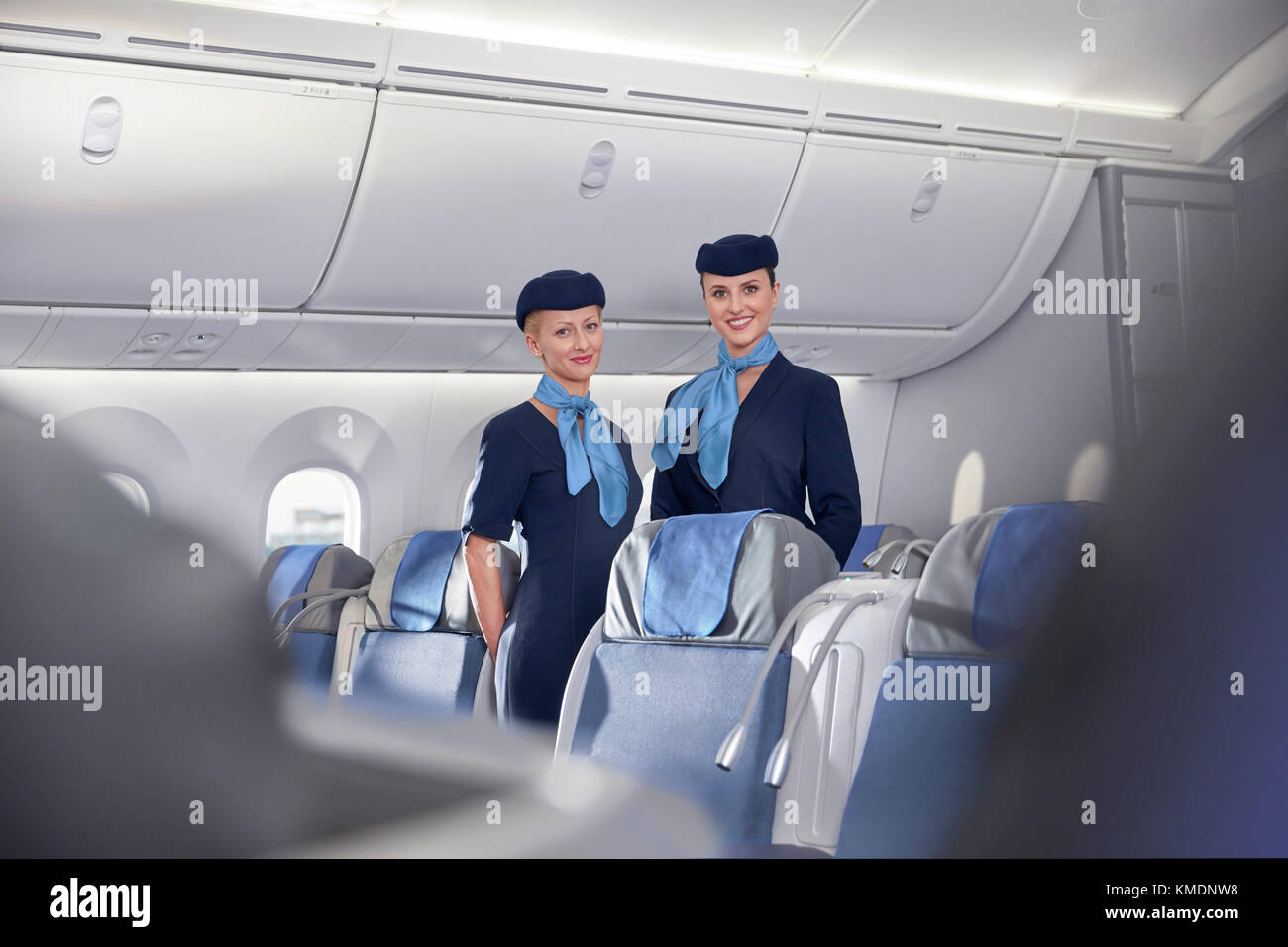 Portrait lächelnd, selbstbewusste Flugbegleiterinnen im Flugzeug Stockfoto