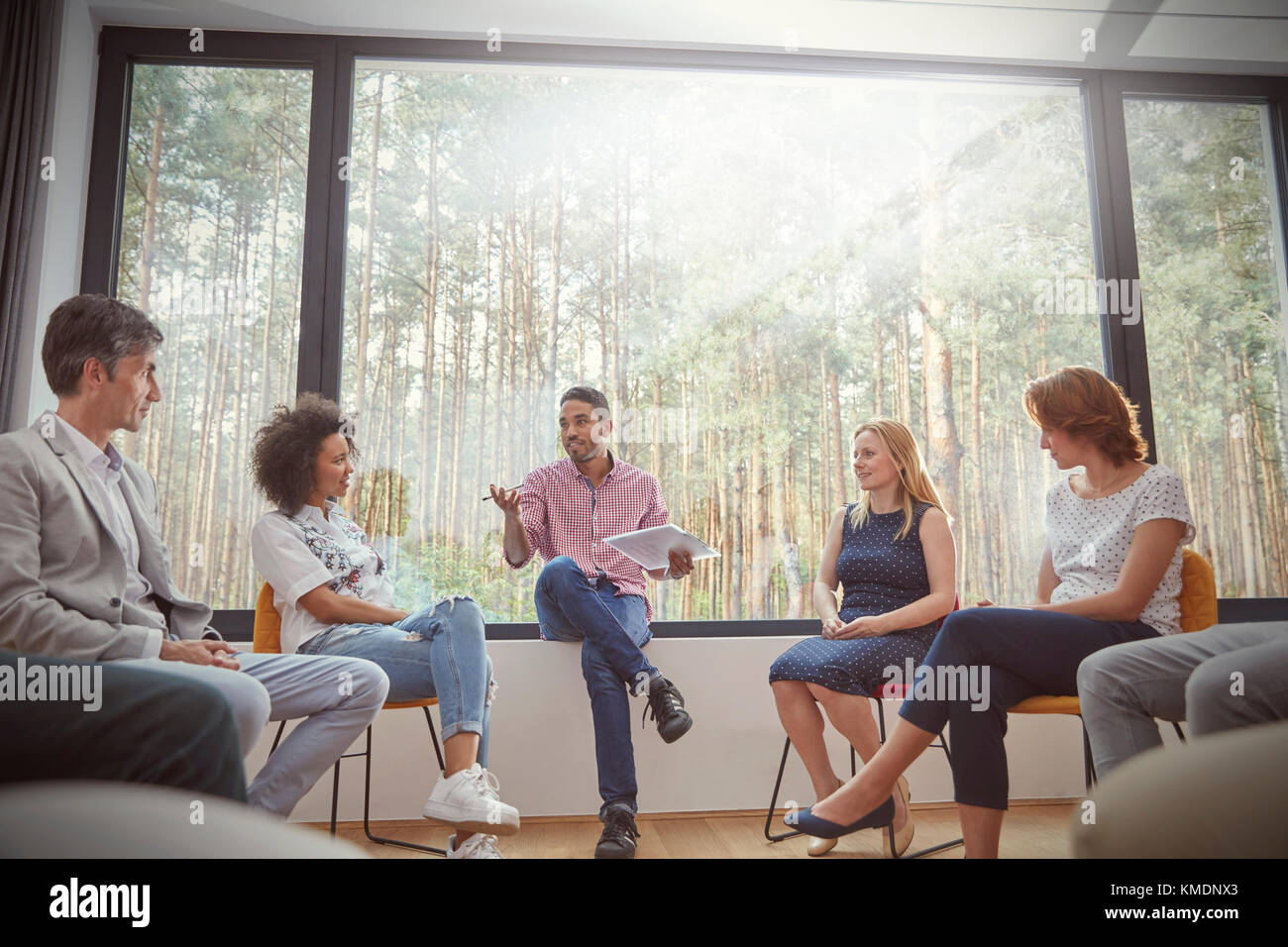 Männlicher Therapeut mit Clipboard führt Gruppentherapie-Sitzung Stockfoto