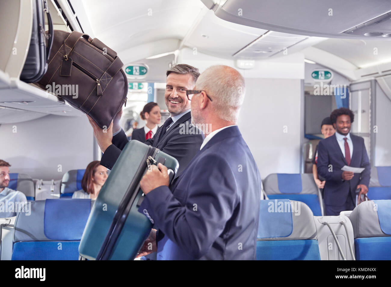 Geschäftsleute, die Gepäck im Flugzeug in das Ablagefach einladen Stockfoto