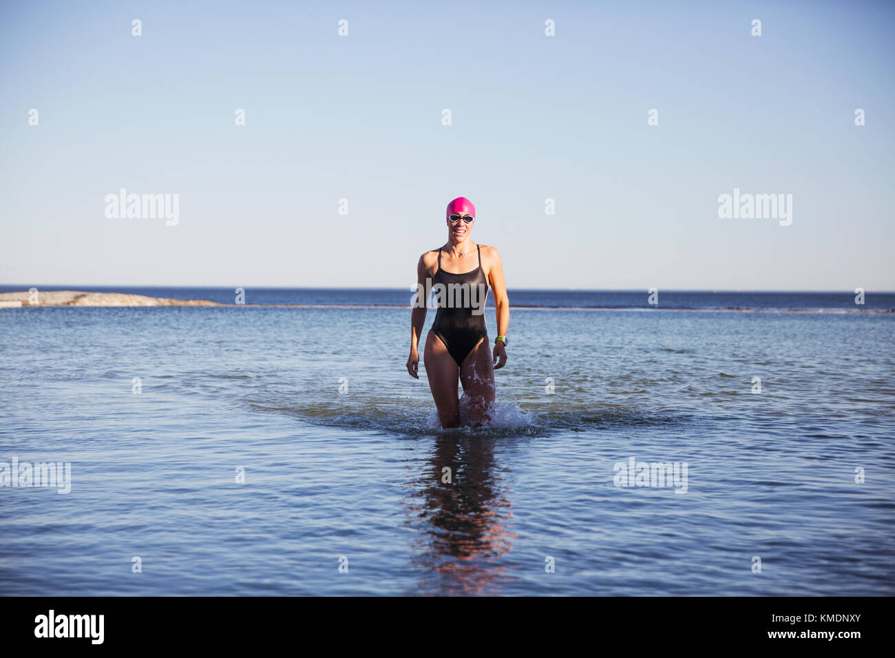 Portrait weibliche Schwimmerin waten, in der sonnigen Meeresbrandung spazieren Stockfoto