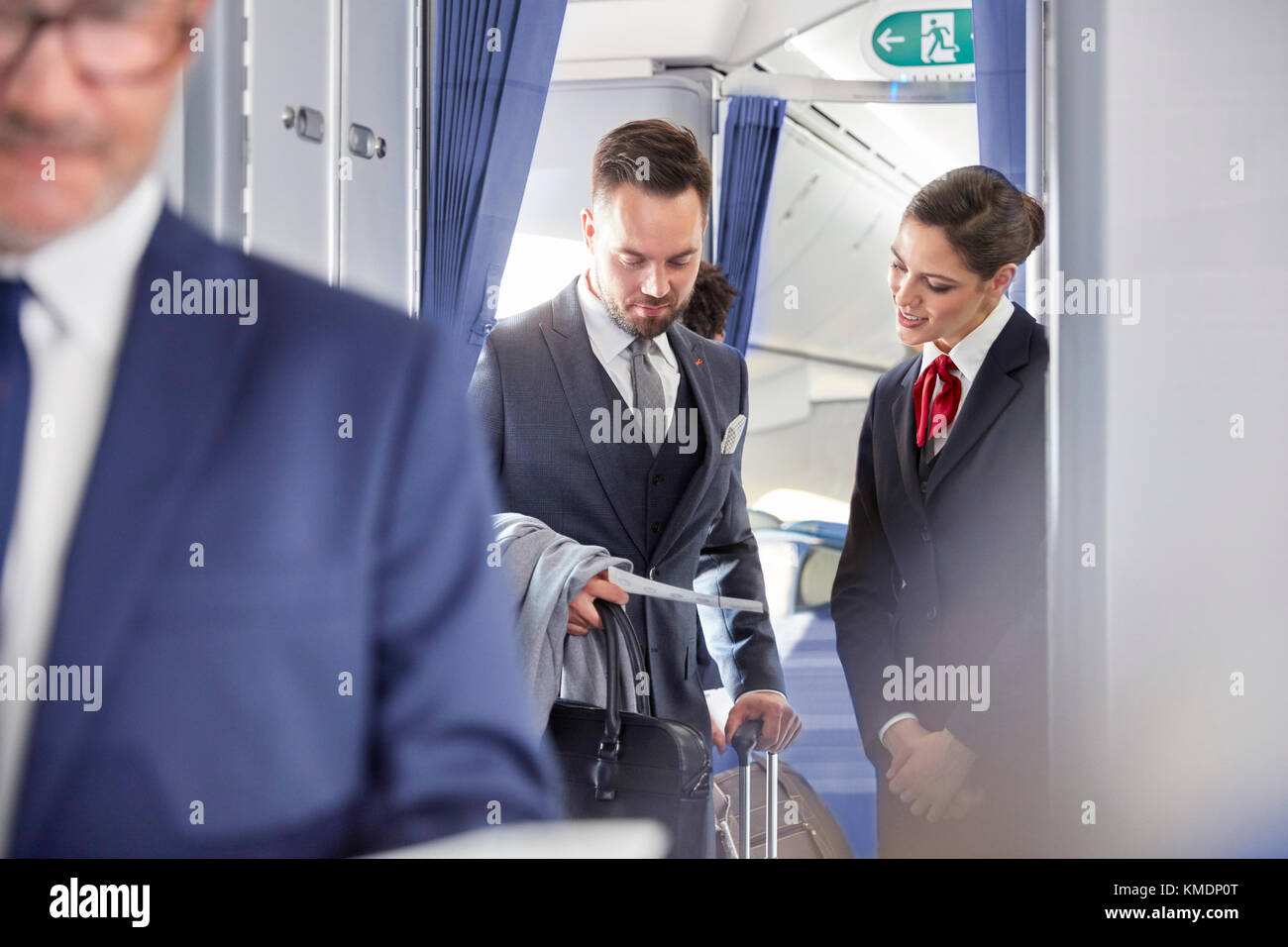 Flugbegleiter hilft Geschäftsmann mit Bordkarte im Flugzeug Stockfoto