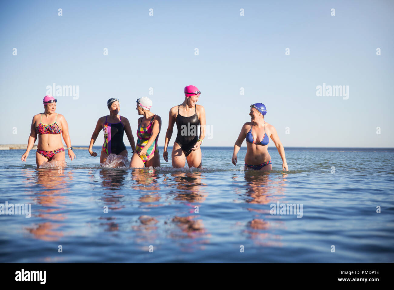 Weibliche Schwimmer im offenen Wasser, die im sonnigen Meer waten Stockfoto