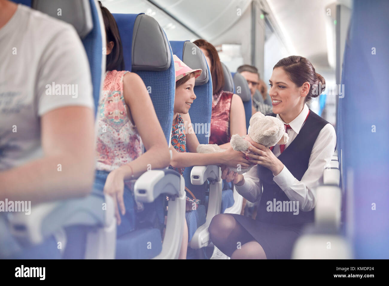 Mädchen zeigt Teddybär zu weiblichen Flugbegleiterin im Flugzeug Stockfoto