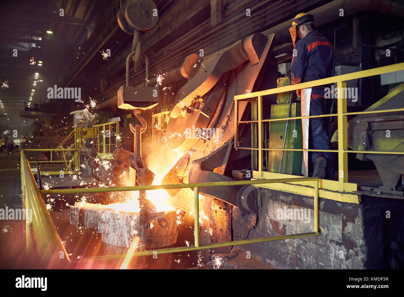 Stahlarbeiter auf Plattform über geschmolzenem Ofen im Stahlwerk Stockfoto