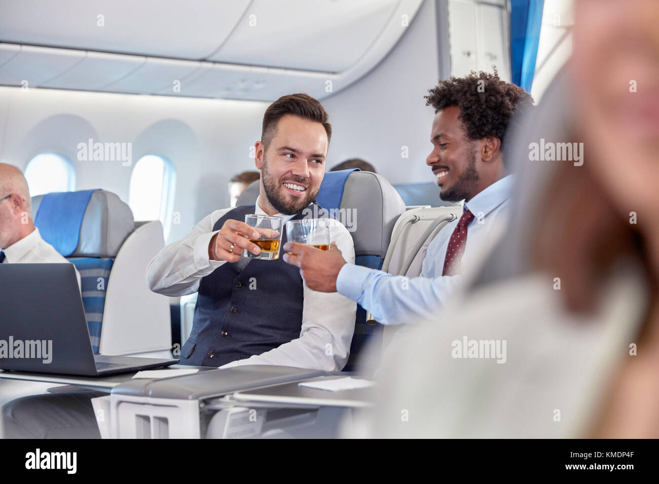 Geschäftsleute toasten Whiskey-Gläser in der ersten Klasse im Flugzeug Stockfoto