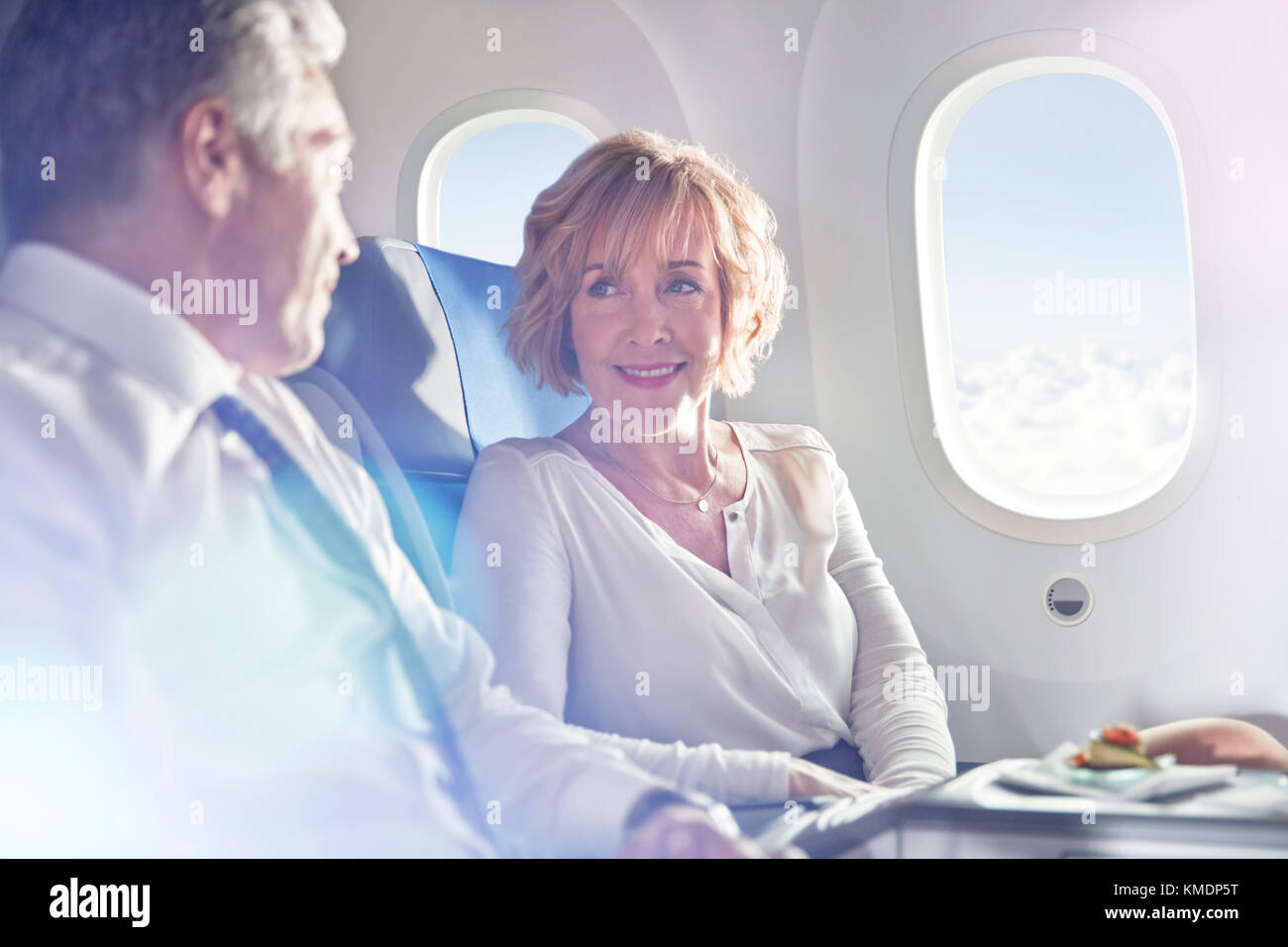 Geschäftsmann und Geschäftsfrau, die im Flugzeug in erster Klasse sprechen Stockfoto