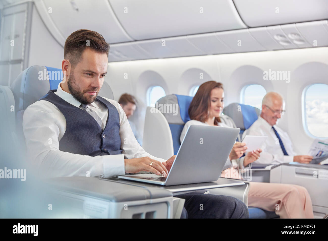 Geschäftsmann, der am Laptop im Flugzeug arbeitet Stockfoto
