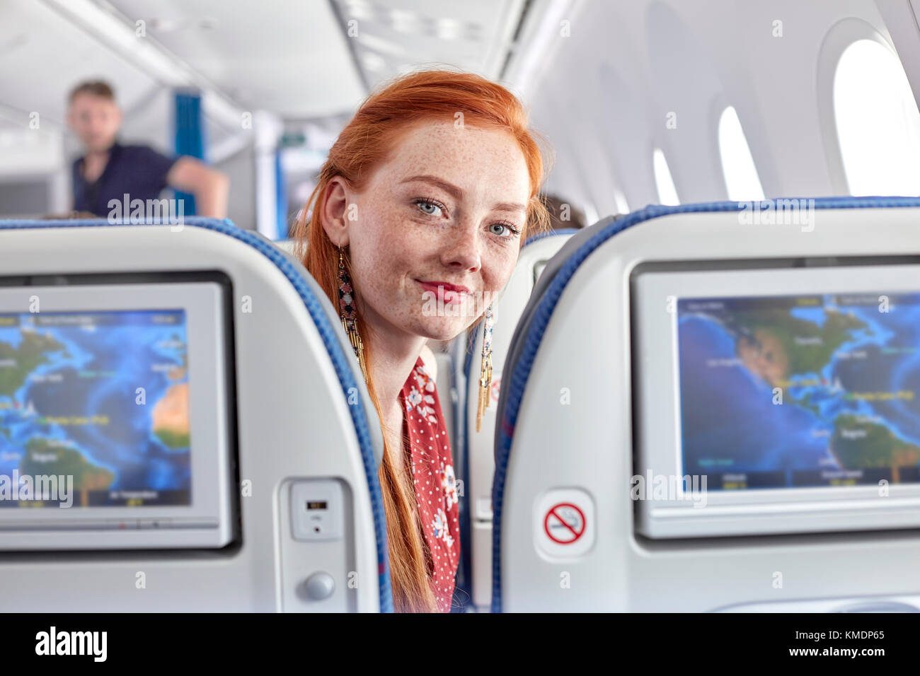 Porträt lächelnde junge Frau mit roten Haaren und Sommersprossen auf Flugzeug Stockfoto