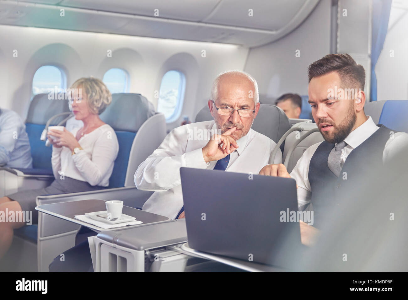 Geschäftsleute, die in der ersten Klasse im Flugzeug am Laptop arbeiten Stockfoto