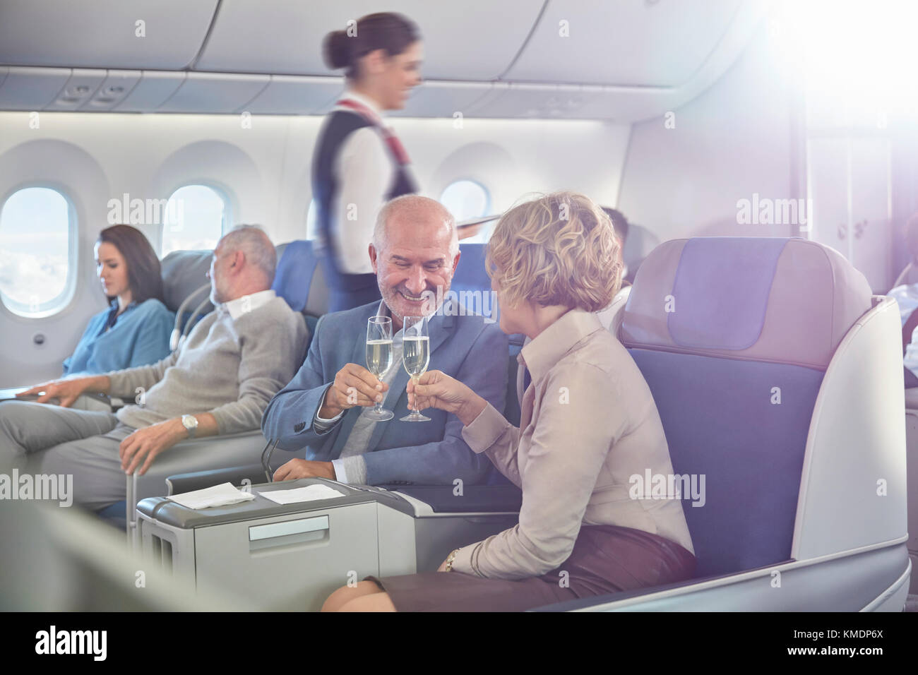 Reifes Paar, das Champagner-Gläser in erster Klasse im Flugzeug toaste Stockfoto