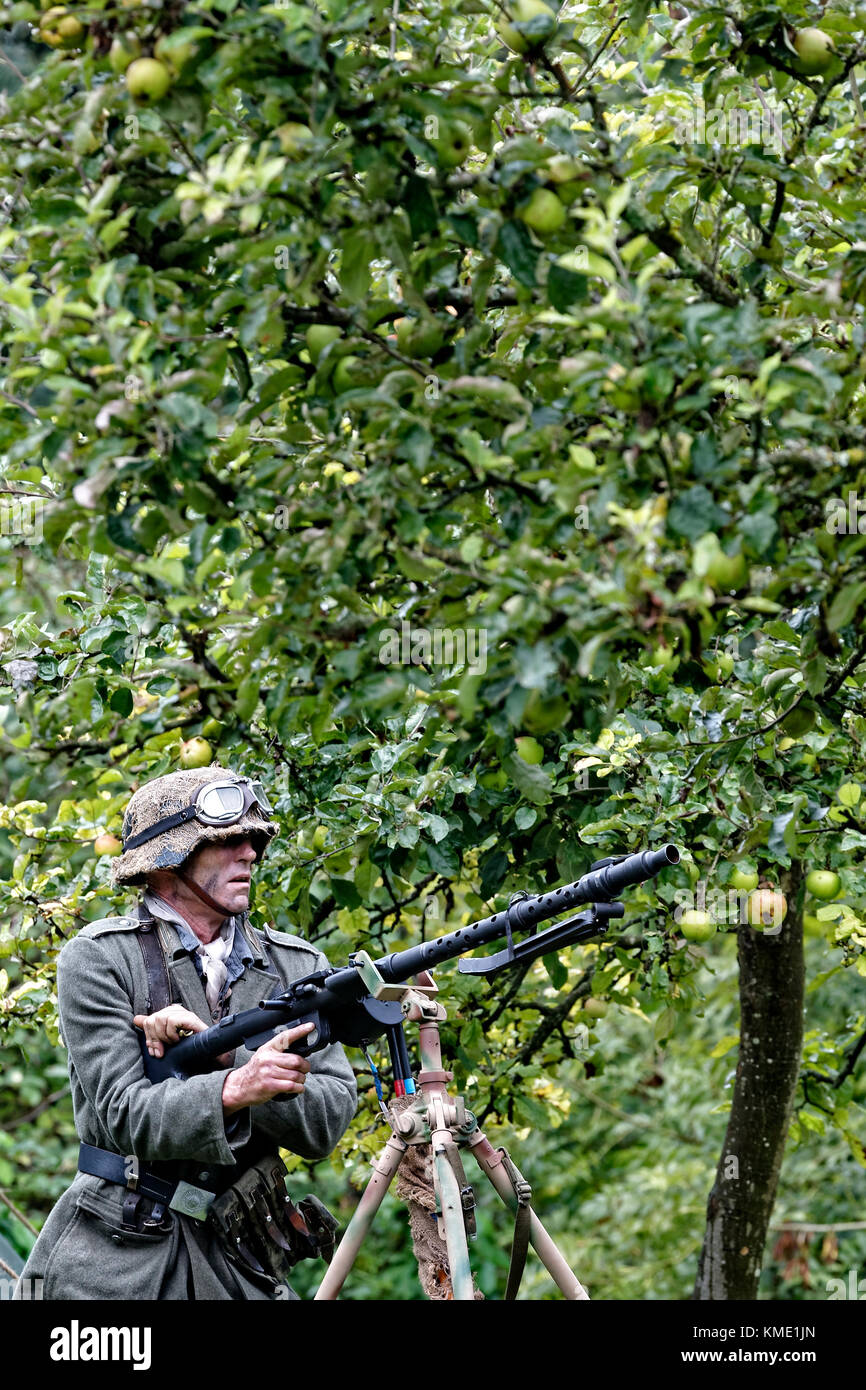 Ein WW2 Wehrmacht Soldat mit MG 34 Infanterie Maschinengewehr in einem Apfelbaum orchard Stockfoto