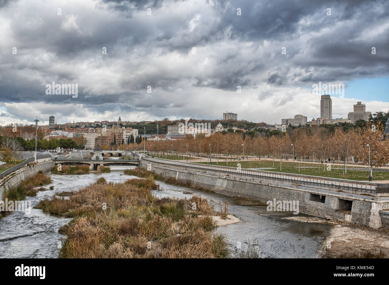 Skyline von Madrid (Spanien) von der Segovia Brücke aus gesehen, einschließlich des Manzanares Flusses und des Madrid Rio Parks. Stockfoto