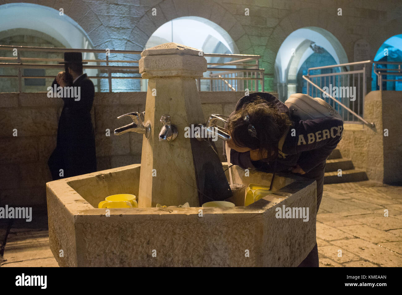 Weibliche Touristen trinken an der Square öffentlichen Brunnen. Während die Juden an der Klagemauer, Jerusalem zu beten. Stockfoto