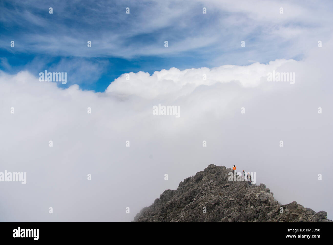 Eine Gruppe von Bergsteigern auf einen kleinen Gipfel von Wolken am Nevado de Toluca Vulkan in Estado de Mexico, Mexiko umgeben. Stockfoto