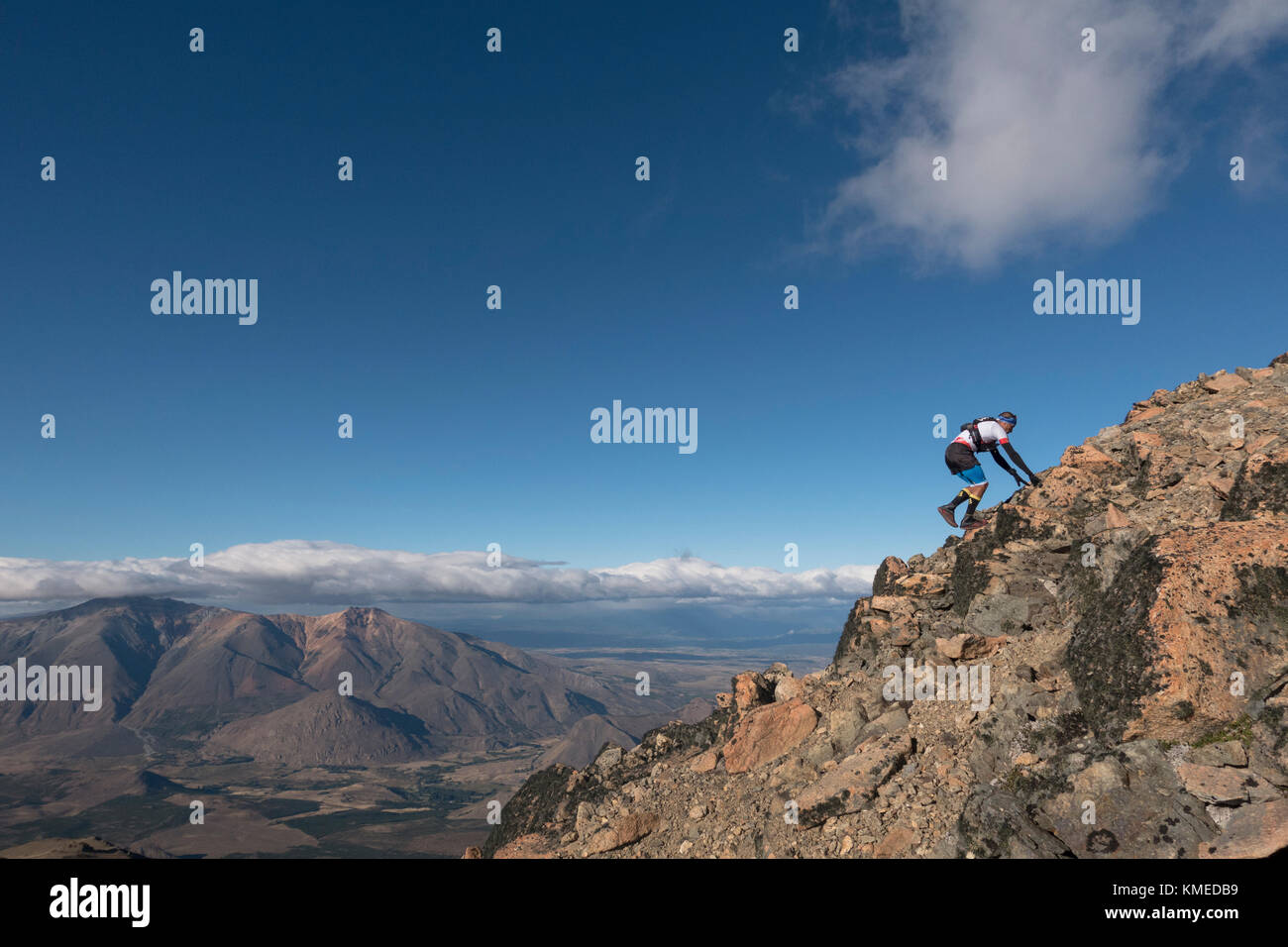Man Klettern rocky mountain gegen Wolken und Himmel, Esquel, Chubut, Argentinien Stockfoto