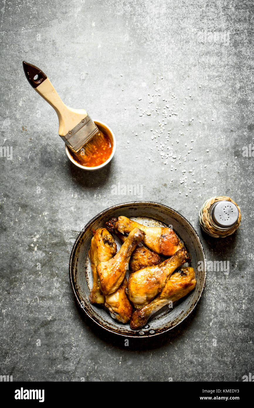 Gebratene Hähnchenschenkel mit Tomatensoße. Auf dem Tisch aus Stein. Stockfoto