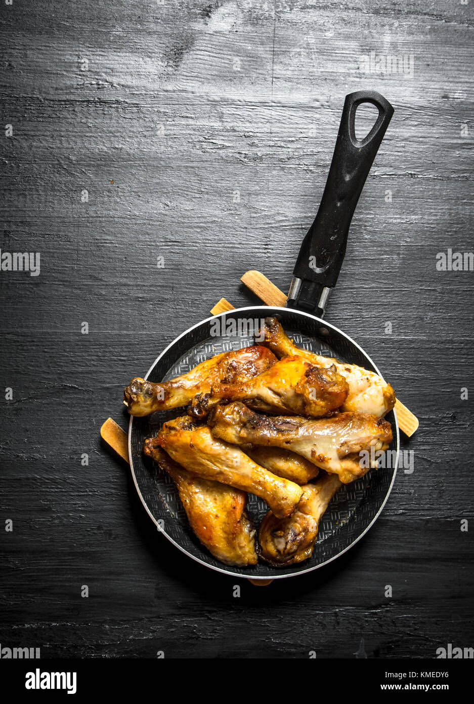 Fried Chicken Beine in der Pfanne. auf einem schwarzen Holz- Hintergrund. Stockfoto