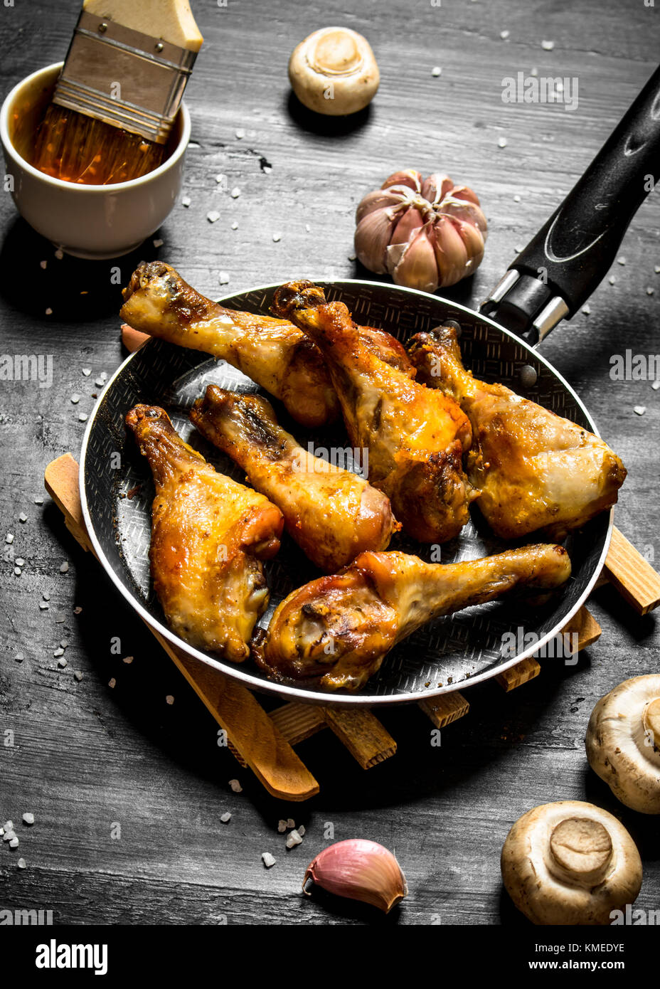 Gebratenes Huhn in einer Pfanne mit Pilzen, Knoblauch und Tomatensauce. Stockfoto
