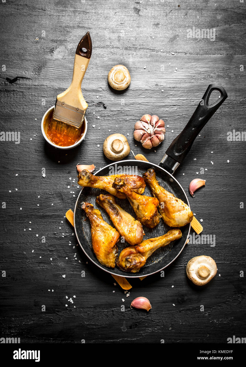 Gebratenes Huhn in einer Pfanne mit Pilzen, Knoblauch und Tomatensauce. Stockfoto