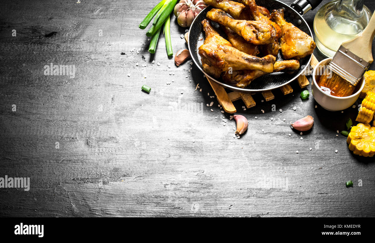 Gebratene Hähnchenschenkel mit Stücken von Mais und Tomatensauce. Stockfoto