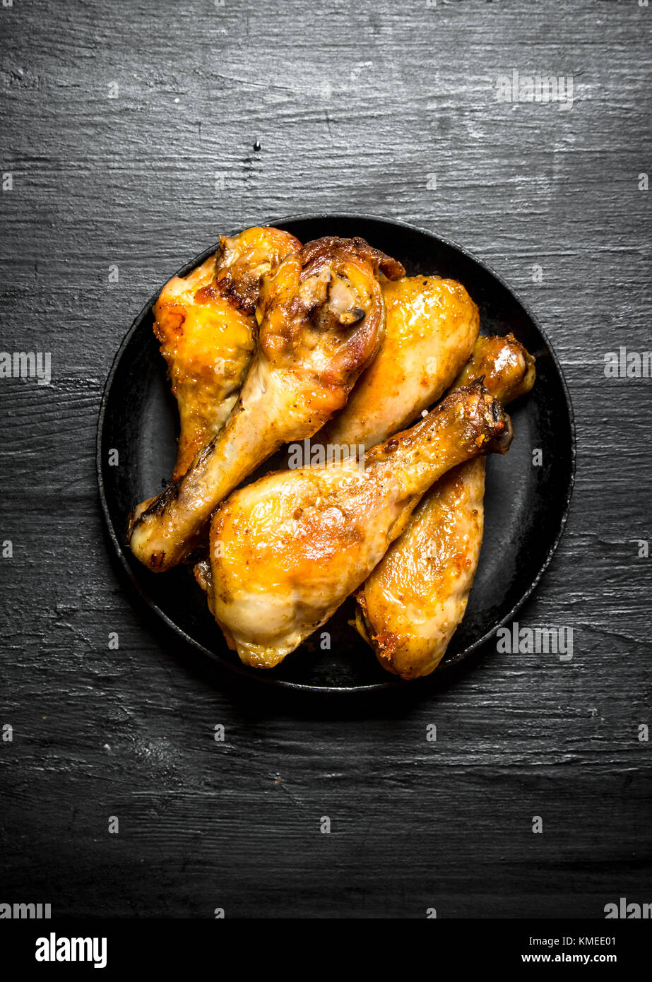 Fried Chicken Beine in der Pfanne. auf einem schwarzen Holz- Hintergrund. Stockfoto