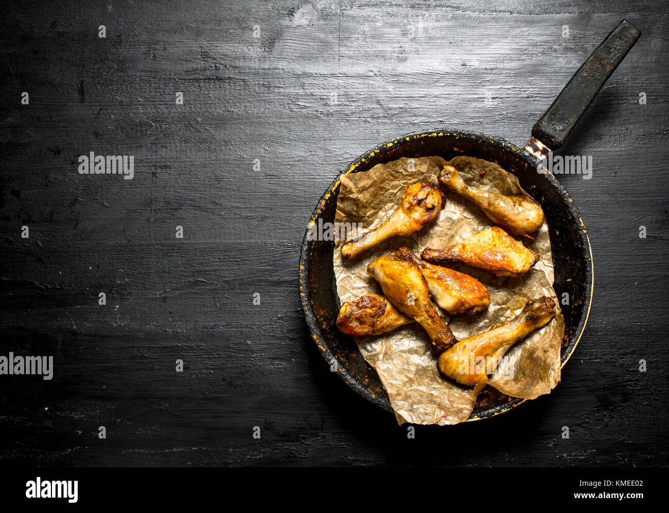 Fried Chicken Beine in der Pfanne. auf einem schwarzen Holz- Hintergrund. Stockfoto