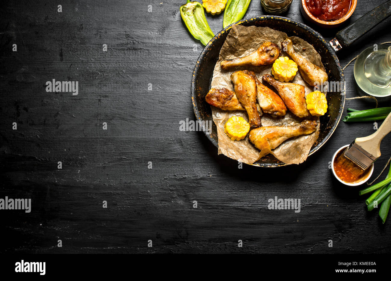 Gebratene Hähnchenschenkel mit Stücken von Mais und Tomatensauce. Stockfoto