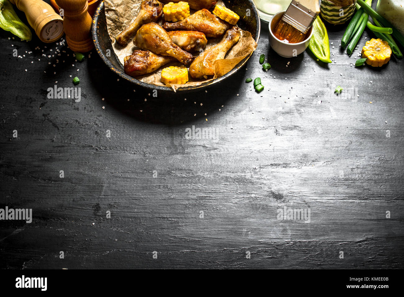 Gebratene Hähnchenschenkel mit Stücken von Mais und Tomatensauce. Stockfoto
