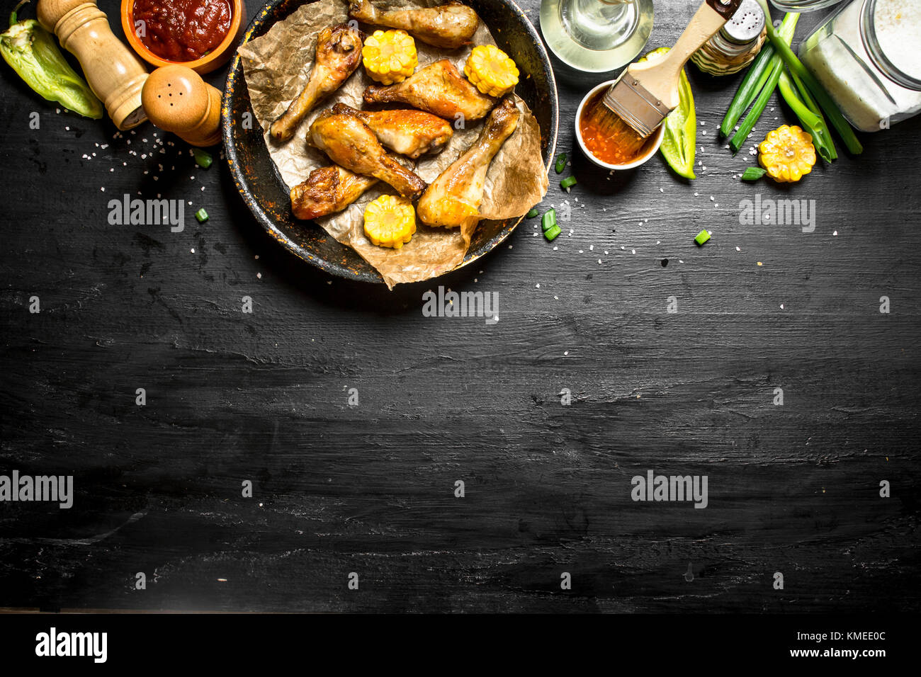 Gebratene Hähnchenschenkel mit Stücken von Mais und Tomatensauce. Stockfoto