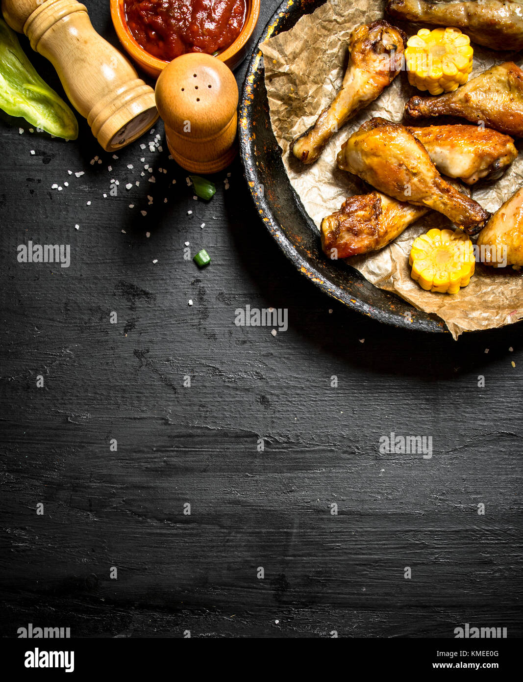 Gebratene Hähnchenschenkel mit Stücken von Mais und Tomatensauce. Stockfoto