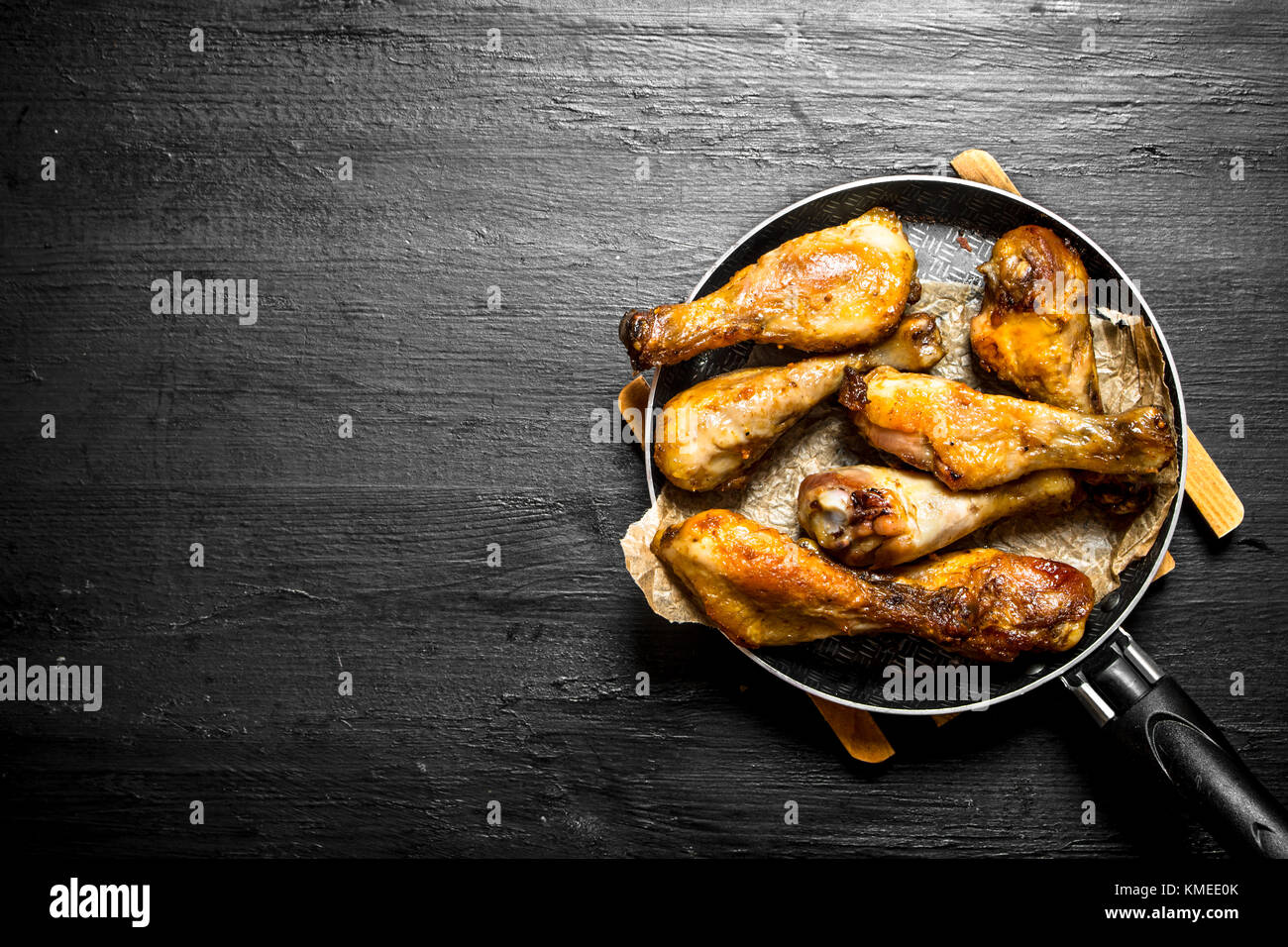 Fried Chicken Beine in der Pfanne. auf einem schwarzen Holz- Hintergrund. Stockfoto
