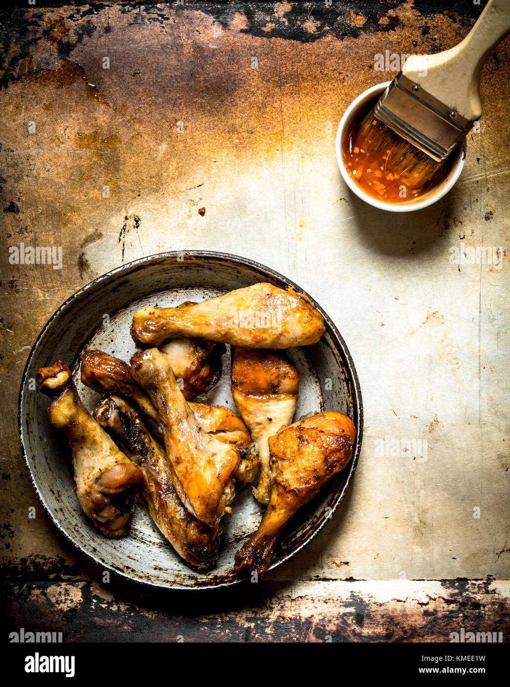 Legen Sie das Huhn in der Pfanne mit Tomatensauce und Pinsel auf einem alten rustikalen Hintergrund. Stockfoto