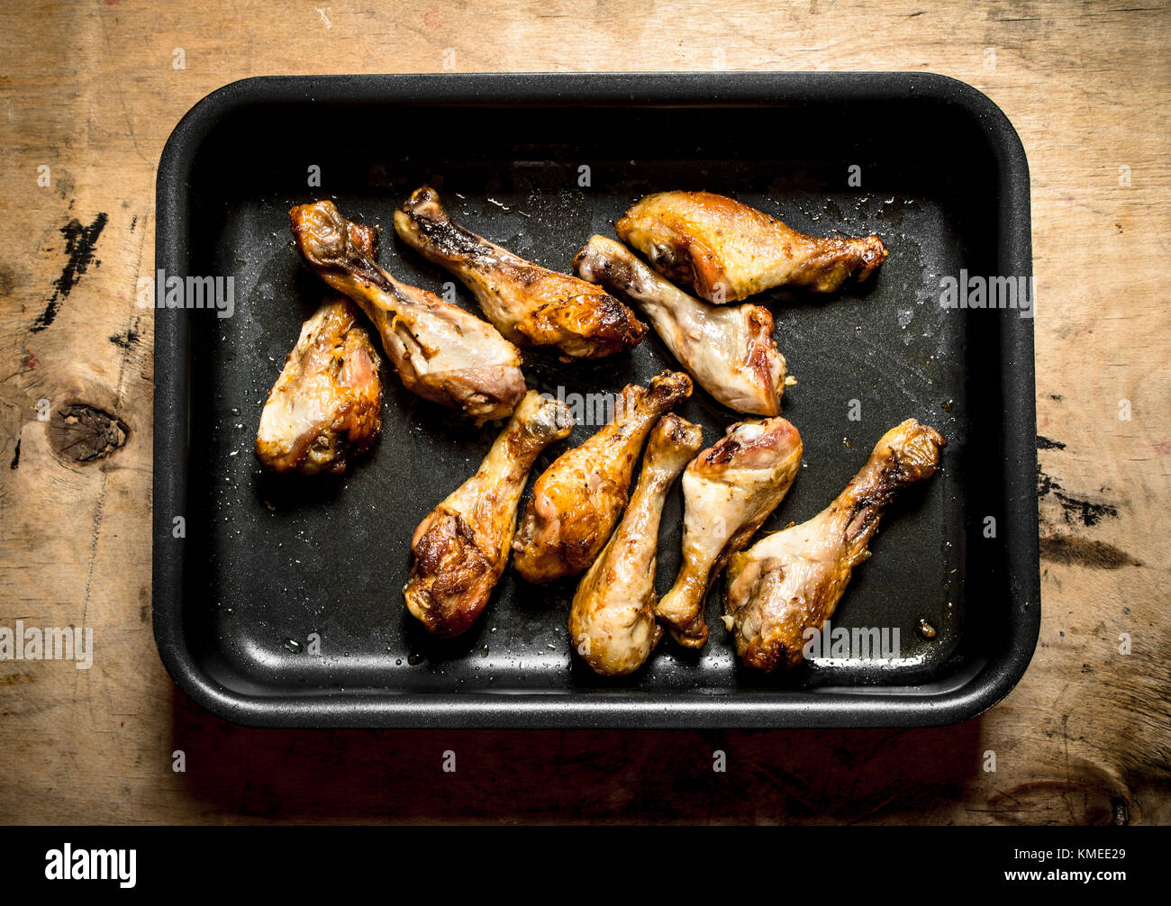 Hähnchenschenkel auf dem Backblech. Auf einem Holztisch. Stockfoto